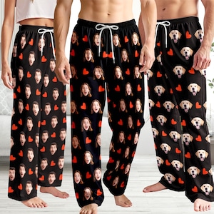 May include: Black pajama pants with a white drawstring. The pants feature a repeating pattern of surprised faces and red hearts. Another pair of pants has a repeating pattern of yellow Labrador faces and red hearts.