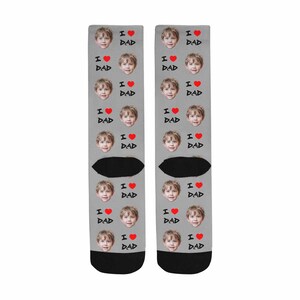 May include: A pair of gray socks with a repeated pattern of a child's face and the text "I love Dad" with a red heart.