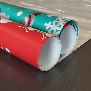 May include: Two rolls of wrapping paper, one red with white polka dots and one green with white snowflakes. The rolls are partially unrolled and the ends are overlapping.