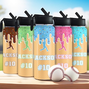 May include: Five water bottles with black lids and straws, featuring baseball-themed designs. Each bottle has a waffle cone pattern, a baseball player silhouette, and the text "JACKSO" and "#10". The tops have colorful dripped icing.