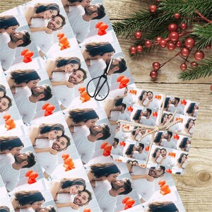 May include: White wrapping paper with a repeating pattern of a couple kissing. The couple are in a white room with red balloons. The wrapping paper is ideal for a romantic gift.
