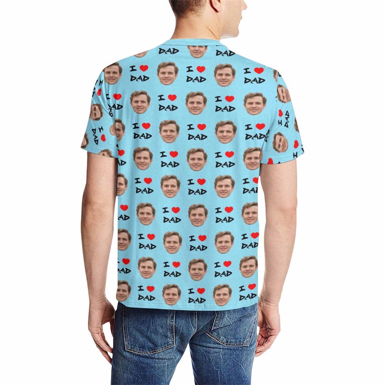 May include: A light blue t-shirt with a repeating pattern of a man's face and the words "I love Dad" in black text with a red heart.