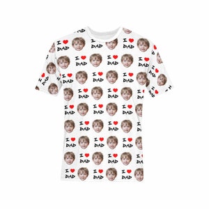 May include: White t-shirt with a repeating pattern of a child's face and the text "I love Dad" in black with a red heart.