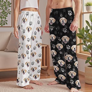 May include: White pajama pants with a repeating pattern of golden retriever faces and gray paw prints. Black pajama pants with the same golden retriever and paw print pattern are also shown.