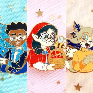 May include: Three enamel pins featuring cartoon characters. One pin depicts a character in a blue tuxedo with a magician's hat. Another shows a character in a red hooded cloak holding a basket of apples. The third pin is of a wolf-like character in an orange sweater.