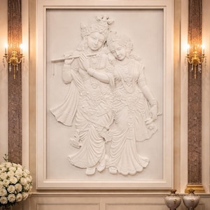 May include: A white relief sculpture of two figures, one playing a flute, set within a white frame. The figures are adorned with detailed clothing and jewelry. The artwork is mounted on a wall with decorative columns and sconces.