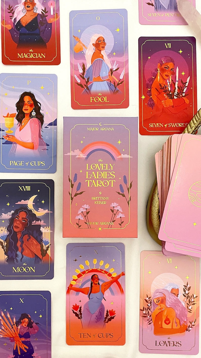 May include: A tarot deck with a rainbow and flowers on the box. The cards feature illustrations of women with colorful backgrounds. The cards are titled "The Lovely Ladies Tarot" by Brittany Keiler.