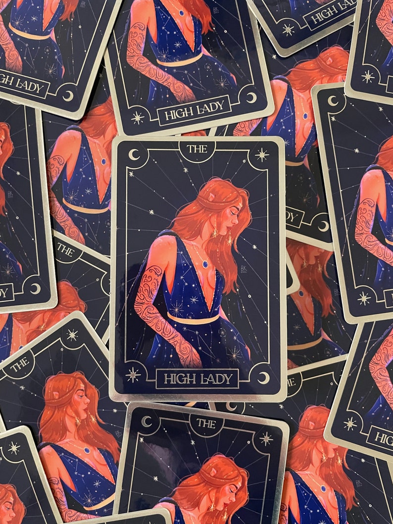 May include: A tarot card with a gold border and a blue background. The card features a woman with red hair and a blue dress. The text on the card reads "The High Lady".