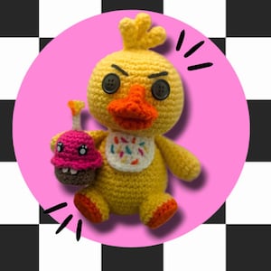 May include: A yellow crocheted chicken plush toy with black eyes and a red beak, holding a pink and brown cupcake with a lit candle. The chicken is wearing a white bib with colourful sprinkles.