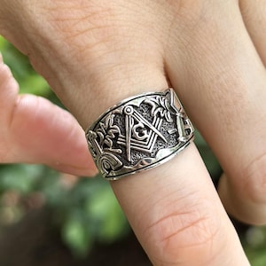 Puede incluir: Un anillo de plata con un diseño detallado que presenta una brújula y un cuadrado, un símbolo común de la masonería.