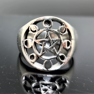 May include: A silver ring featuring a pentagram and moon phases design. The ring is made from sterling silver and has a polished finish.