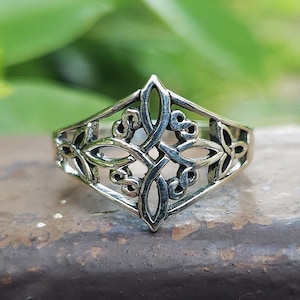 May include: A silver ring with a Celtic knot design. The ring is made of intricate, interwoven loops and has a diamond shape.
