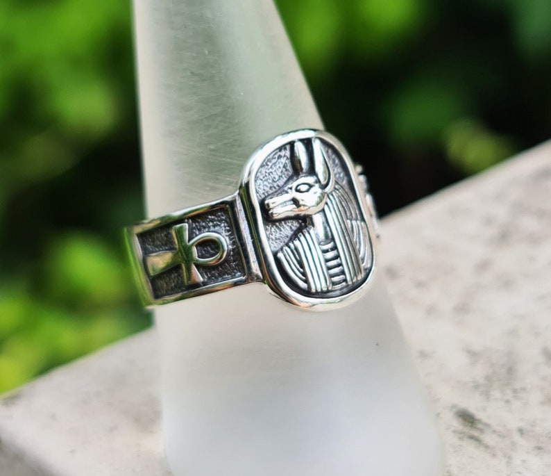 May include: Silver ring with an ankh symbol and an image of an Egyptian god's head.