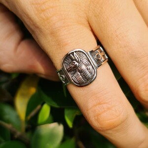 May include: Silver ring with an Anubis head design and an ankh symbol on the band.