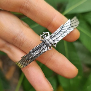 Op de afbeelding: Zilveren armband met een scarabée-ontwerp. De kever heeft vleugels en is gedetailleerd met ingewikkelde gravures.