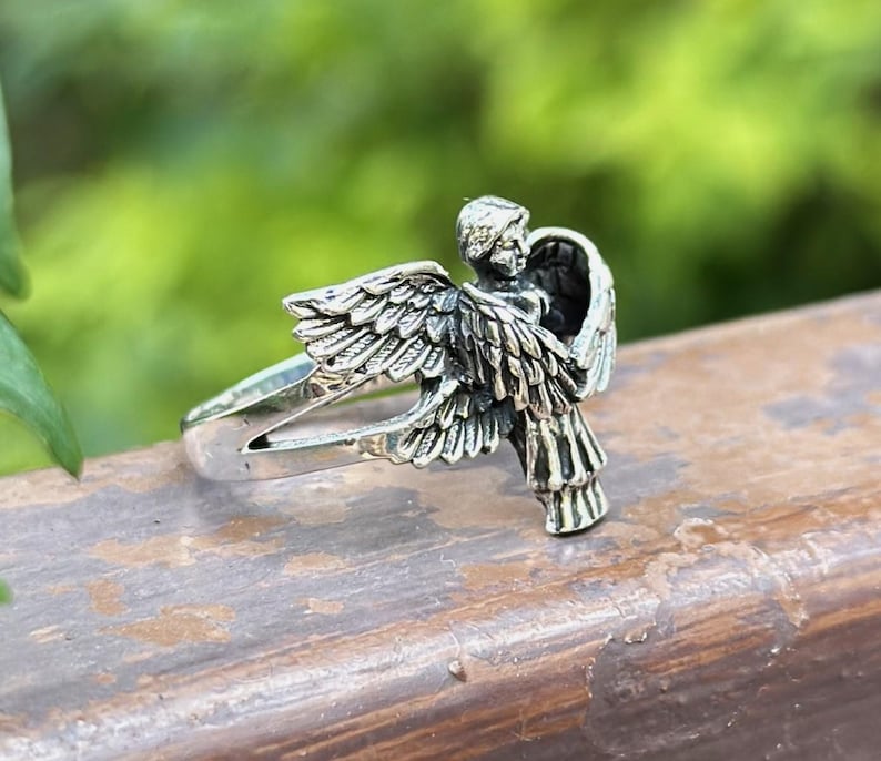 May include: A silver ring with an angel design. The angel is depicted with wings outstretched and a halo. The ring is made of sterling silver and is a great gift for anyone who loves angels.
