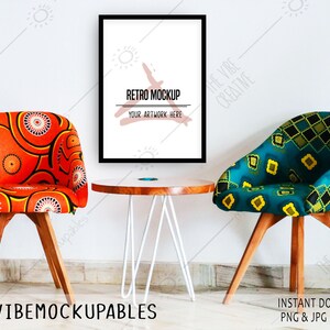 May include: A mockup of a black framed poster with the text "Retro Mockup" and "Your Artwork Here" on a white background. The poster is hanging on a white wall between two chairs with colorful patterned fabric. The chairs are wooden with a light brown finish. A white table with a round wooden top sits in front of the chairs.
