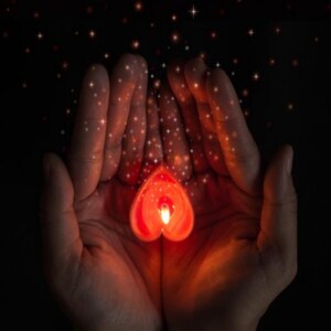 May include: Two hands cupped together holding a red heart-shaped candle with a flickering flame. The hands are surrounded by a soft glow of light and sparkle.