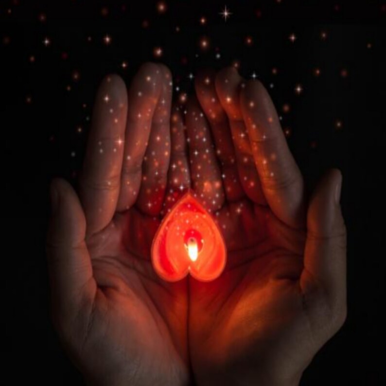 May include: Two hands cupped together holding a red heart-shaped candle with a flickering flame. The hands are surrounded by a soft glow of light and sparkle.