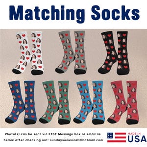 May include: Six pairs of colorful socks with a heart pattern and a face printed on them. The socks are arranged in two rows of three pairs. The socks are made in the USA.