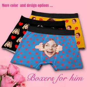 May include: Three pairs of boxer shorts with different designs. One pair is black with red hearts and a repeated image of a person's face. Another pair is yellow with a repeated image of a person's face and red lips. The third pair is blue with red hearts and a repeated image of a person's face peeking out from behind the fabric. The text "Boxers for him" is at the bottom of the image.