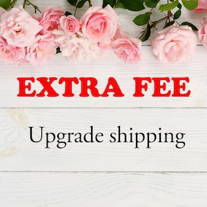 May include: Image with the words "EXTRA FEE" in red, above the words "Upgrade shipping" in black. The background is a white wooden surface, with pink roses and green leaves at the top.