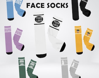 May include: A set of custom face socks with various designs. The socks are white, black, yellow, purple, green, and gray. Some socks feature text like "Your Logo", "Best Dad", and "Jennifer Artman". Other socks feature images of a graduation cap, a mustache, and a face.