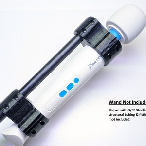 May include: A black 3D printed mount for a white Magic Wand massager. The mount is designed to attach to a 3/8 inch steel tube. "Wand Not Included" and "Shown with 3/8" Steeltek structural tubing & fittings. (not included)" are written in black text on a white background.