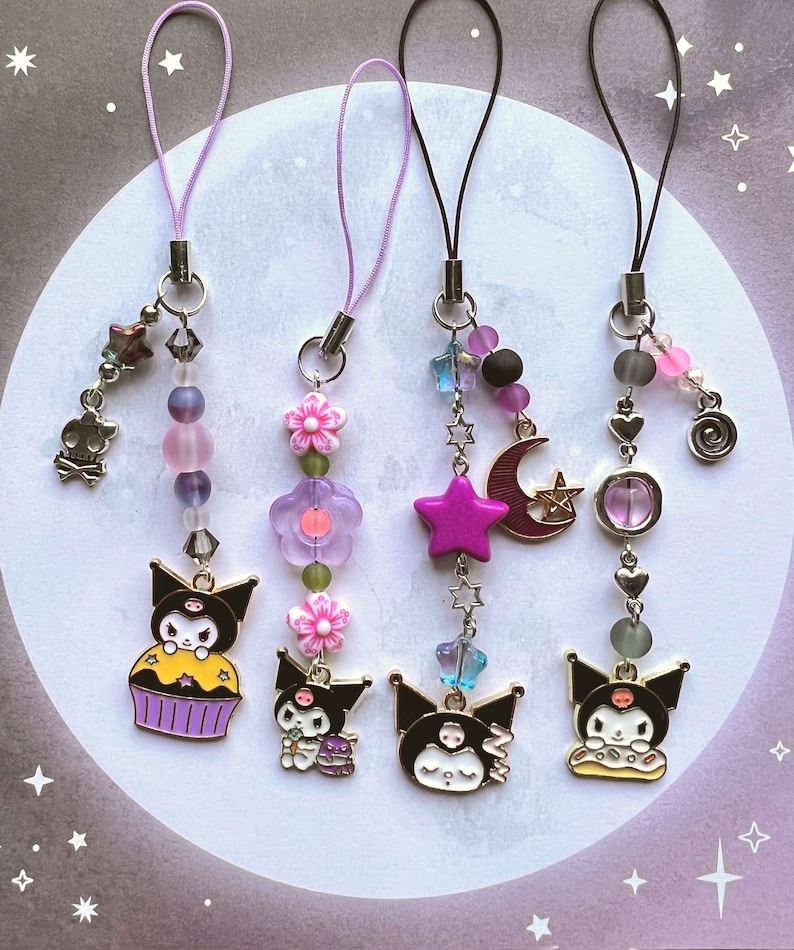 Pode incluir: Tr&ecirc;s pulseiras de telefone com amuleto Hello Kitty em preto e branco com contas e amuletos de diferentes cores. Os amuletos incluem um cupcake, uma estrela e uma lua crescente.