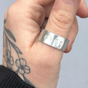 May include: A silver ring with the word "DYKE" engraved on it.
