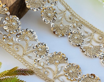 May include: Gold embroidered lace trim featuring floral and leaf designs. The trim is adorned with sequins, faux pearls, and clear rhinestones. The lace is approximately 2 inches wide and is suitable for various craft projects.