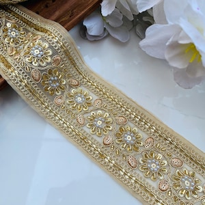 Può includere: Bordura di perline dorate e avorio con un motivo floreale. La bordura è realizzata con paillettes, perline e filo. È perfetta per aggiungere un tocco di eleganza a qualsiasi progetto.