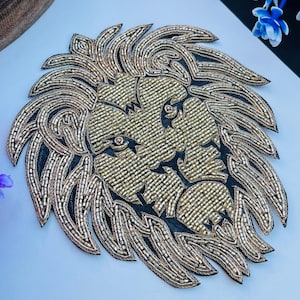 May include: A gold beaded lion head applique with a black background. The lion's mane and face are intricately detailed with small, shiny beads. The applique is likely for embellishing clothing or accessories.