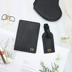 May include: A set of black leather travel accessories with gold initials "FP". The set includes a passport holder, a luggage tag, and a heart-shaped cosmetic bag.