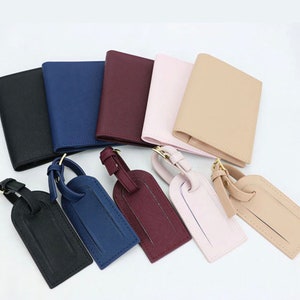 May include: Set of six leather luggage tags in various colors, including black, navy blue, burgundy, pink, beige, and brown. Each tag has a gold metal loop and a leather strap.