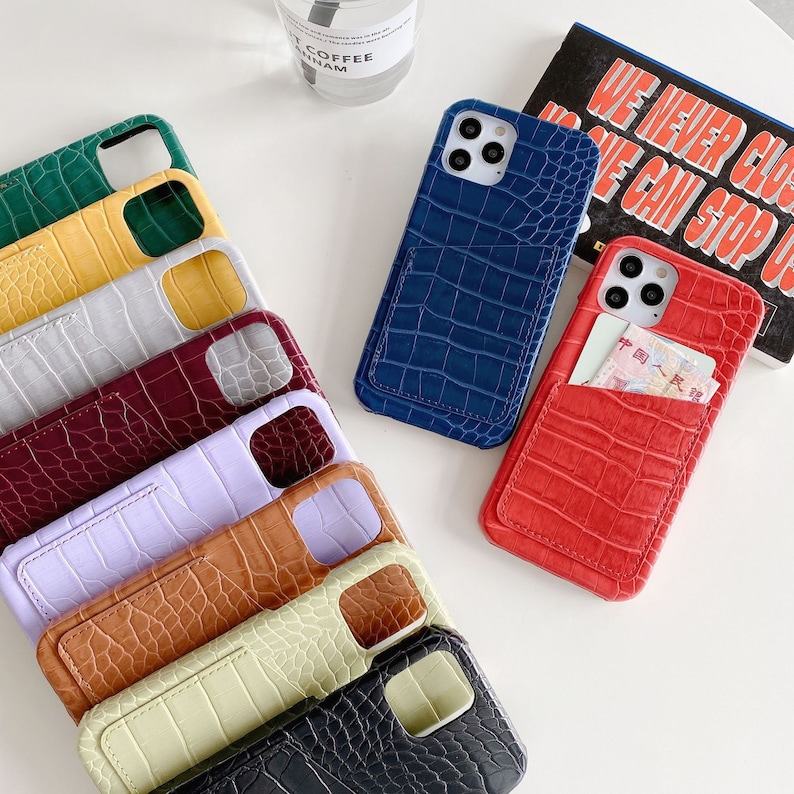 May include: A collection of ten phone cases with a crocodile skin pattern and a built-in card slot. The cases are in various colors, including green, yellow, gray, red, purple, brown, beige, black, and blue.