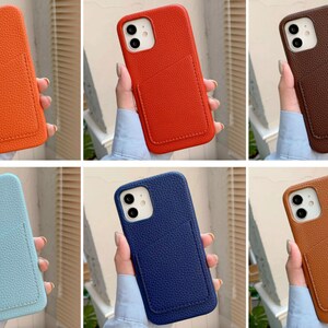 May include: Six different colored phone cases with a built-in card holder. The cases are made of textured leather and come in orange, red, brown, light blue, dark blue, and tan.