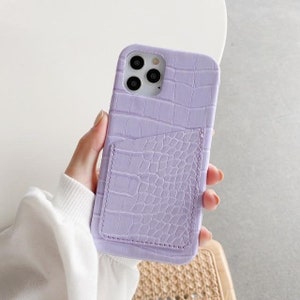 May include: A lavender phone case with a crocodile-embossed texture and a built-in card slot.