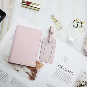 May include: A pink passport holder and matching luggage tag with gold lettering that says "CB".