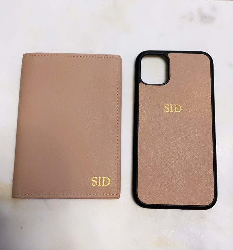 May include: Two matching personalized phone cases and a wallet in a light pink color with the name "SID" embroidered in gold on each item.