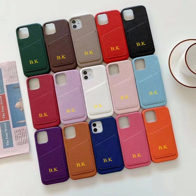 May include: Assortment of 15 phone cases in various colors, each with a pocket on the back and the initials "B.K." in gold lettering.