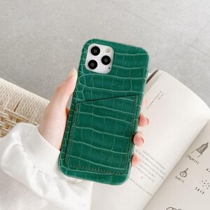May include: A green crocodile-embossed phone case with a built-in card slot.