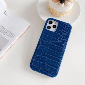 May include: A blue phone case with a crocodile pattern and a built-in card holder.