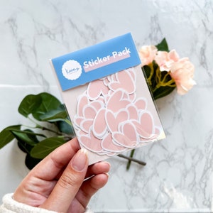 May include: A sticker pack with the text "Sticker Pack" and the logo "Kacey's Creations" on a blue background. The pack contains pink heart-shaped stickers.