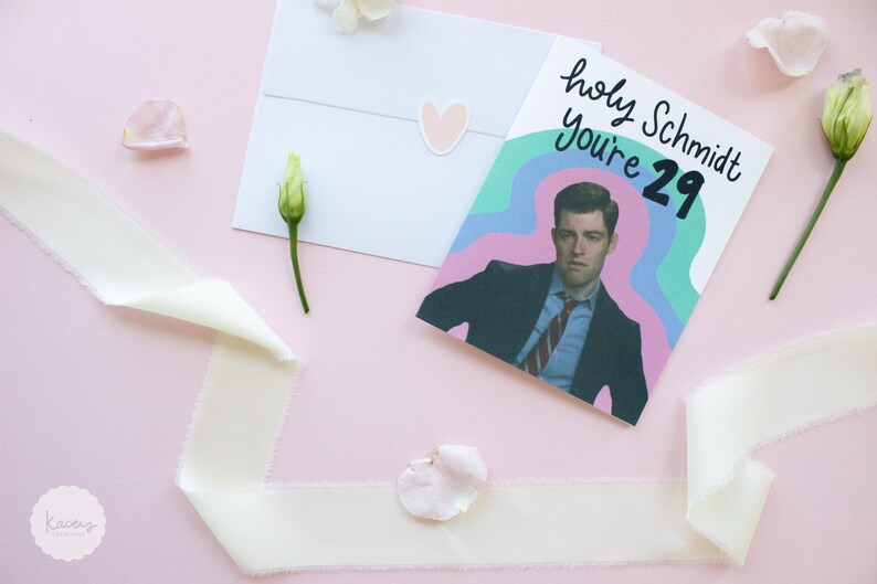 May include: A greeting card featuring a photograph of a man in a dark suit and red striped tie, set against a background of wavy teal, purple, and pink lines. The text reads holy Schmidt You're 29 in black script and block lettering.