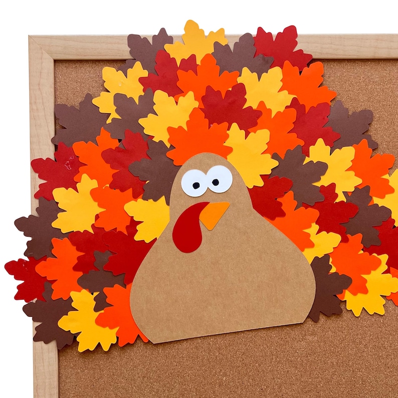 Puede incluir: Un recorte artesanal de pavo hecho de cartulina color canela con una car&uacute;ncula roja, un pico naranja y dos ojos blancos con pupilas negras. El pavo presenta una gran cola en abanico hecha de hojas de arce de papel superpuestas en tonos rojo, naranja, amarillo y marr&oacute;n.