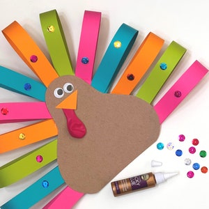 May include: A brown paper turkey craft with a colorful paper tail. The tail is made of strips of paper in various colors, including green, orange, pink, and blue. The turkey has googly eyes and a red beak. There are colorful sequins scattered around the turkey.