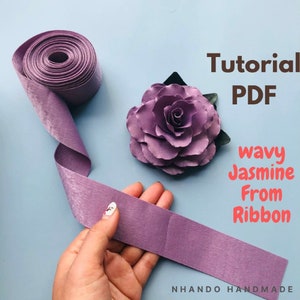 May include: Purple satin ribbon with a tutorial PDF for making a wavy jasmine flower from ribbon. The text "Tutorial PDF" and "wavy Jasmine From Ribbon" is displayed on the image. The image also shows a finished flower made from the ribbon.