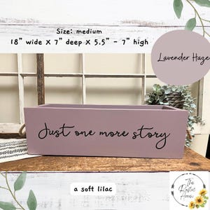 May include: A medium-sized, soft lilac wooden box with the text "Just one more story" in black script. The box is 18 inches wide, 7 inches deep, and 5.5 to 7 inches high. The box is labeled "Lavender Haze".