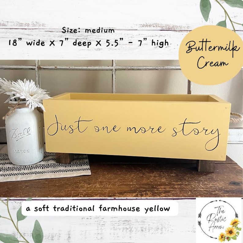 May include: A medium-sized, soft yellow wooden box with the text "Just one more story" in black script. The box is 18 inches wide, 7 inches deep, and 5.5 to 7 inches high. A mason jar with white flowers sits to the left.